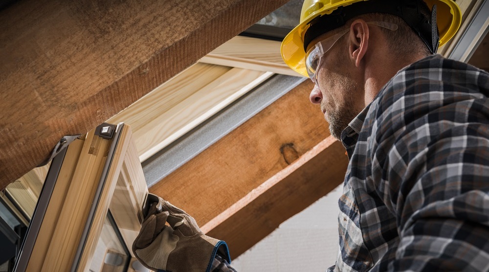 Dachfenstermonteur setzt ein neues Dachfenster im ausgebauen Dachgeschoß ein